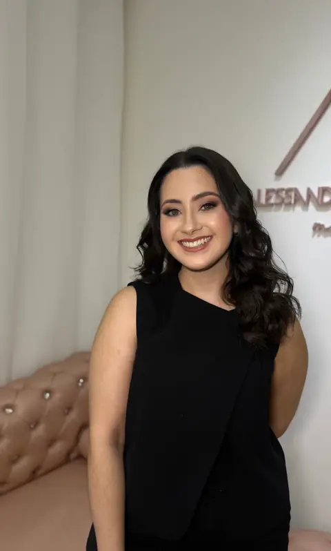 Cliente sorrindo de cabelo escuro em ondas e blusa preta, no lounge do espaço