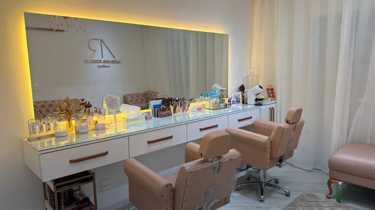 Bancada de maquiagem do espaço com espelho iluminado, gavetas brancas e cadeiras rosadas