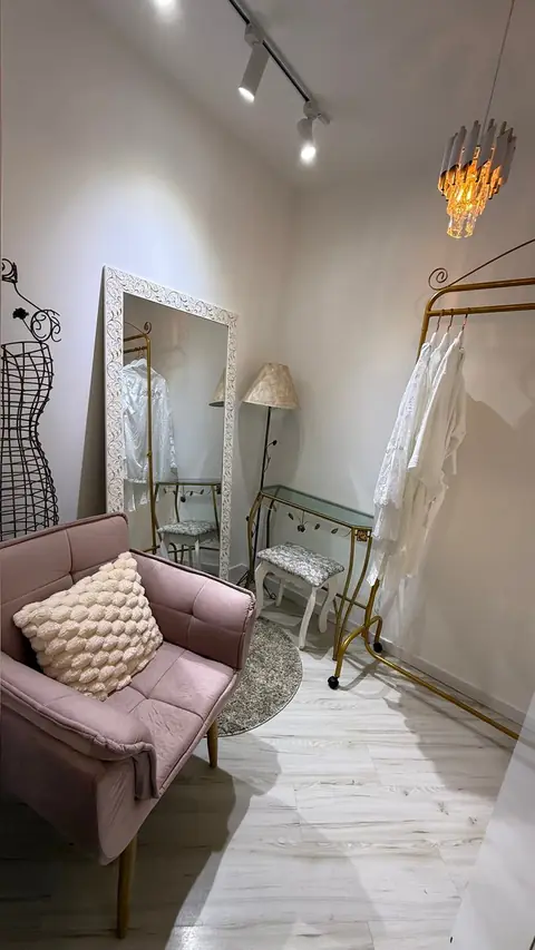 Sala da noiva no espaço AR Concept, com sofá rosa, espelho, arara e vestido pendurado