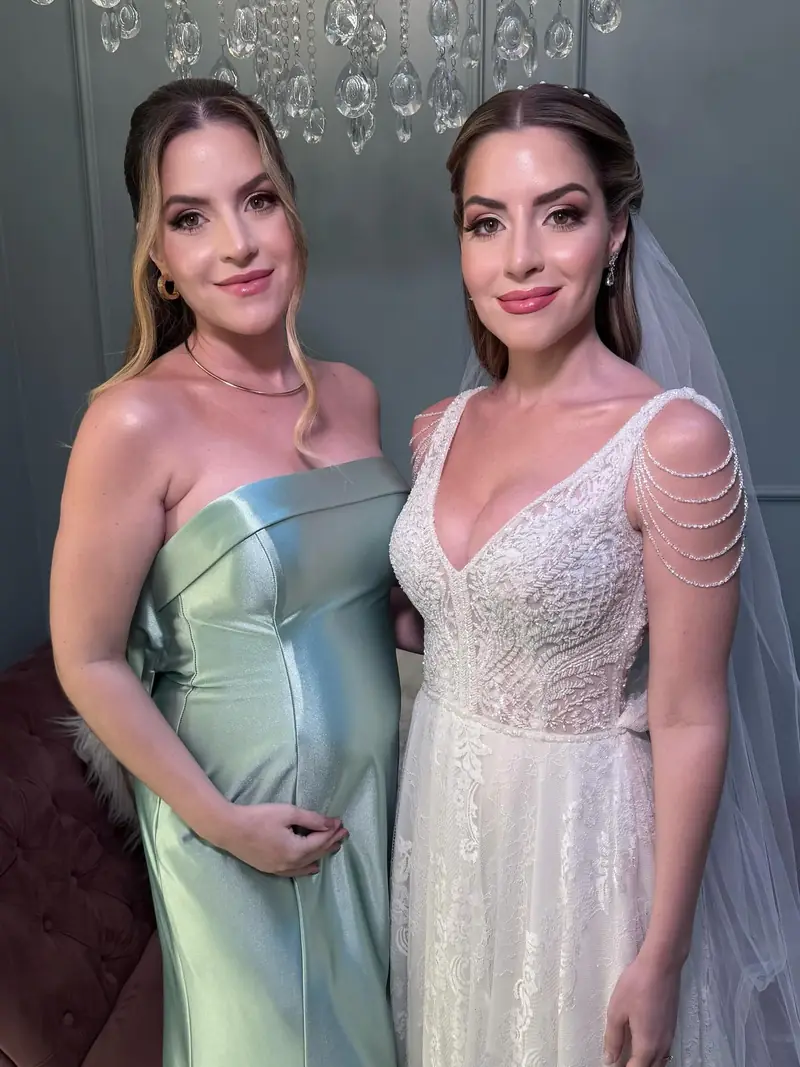Noiva e a irmã gêmea, de vestido acetinado verde menta, lado a lado, maquiadas para o casamento