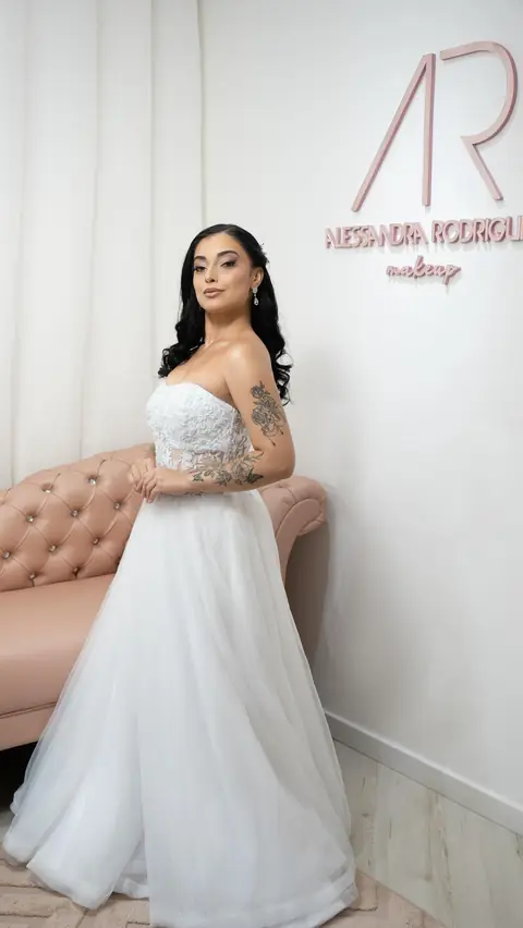 Noiva de cabelo solto e vestido tomara que caia encostada no sofá capitonê rosa do espaço AR Concept