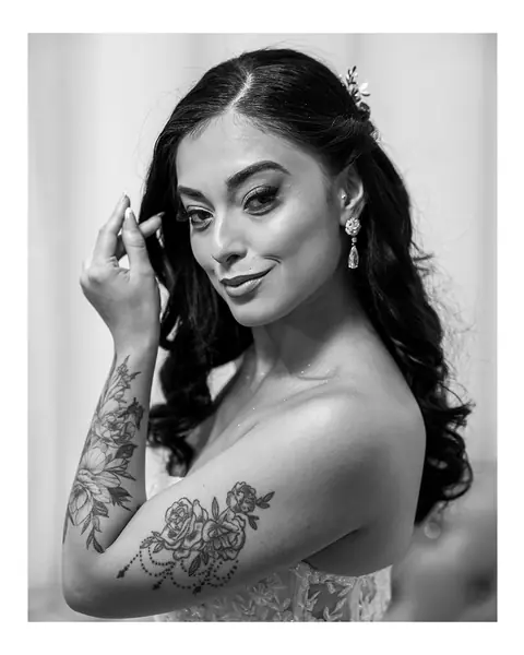 Noiva em preto e branco com a mão no cabelo solto, olhando para a câmera