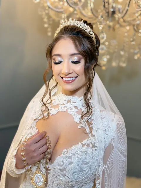 Noiva sorrindo com tiara, véu e vestido de renda, cabelo semipreso com cachos